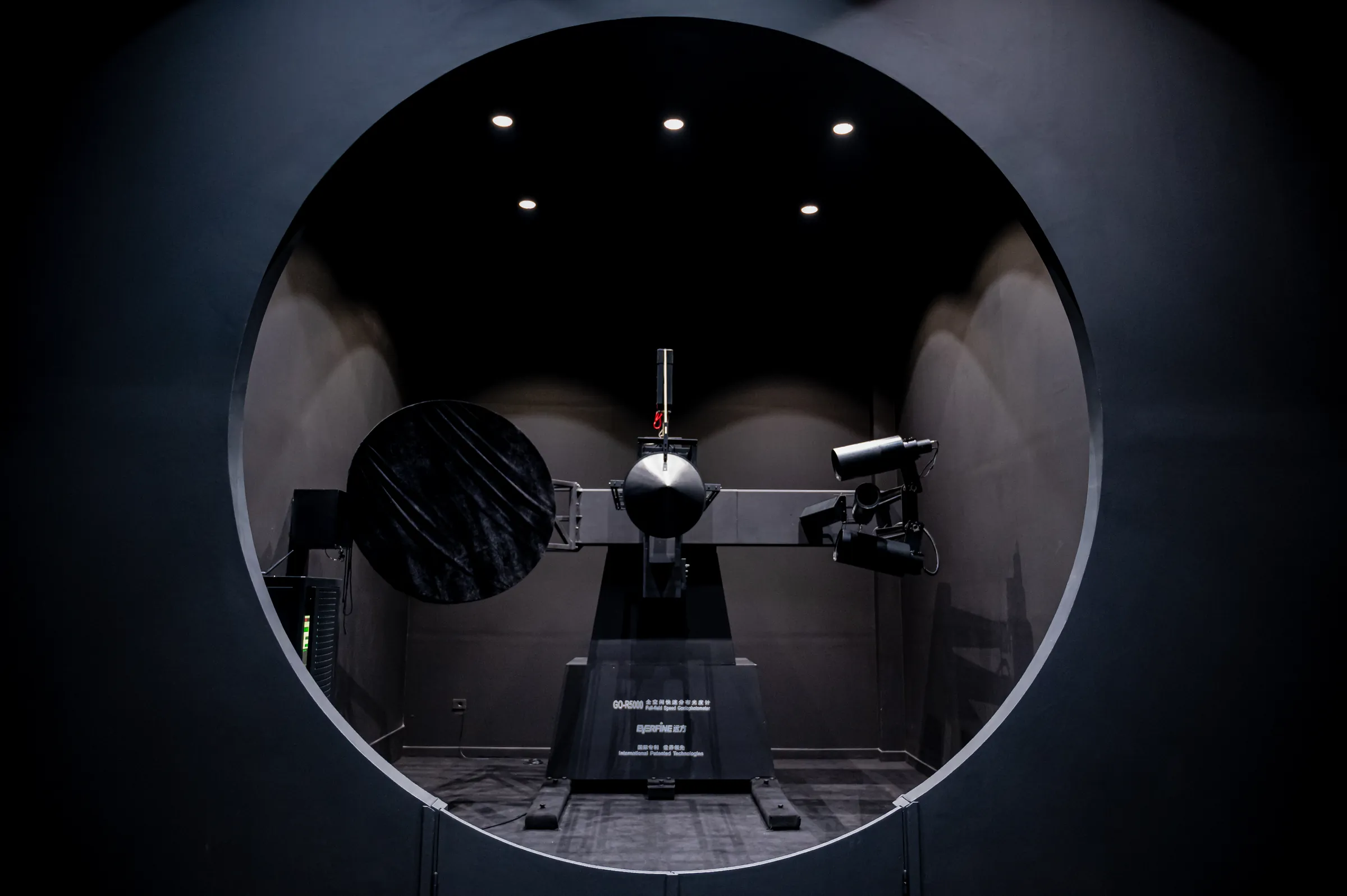 The goniophotometer, seen through the circular port of the laboratory's darkroom.